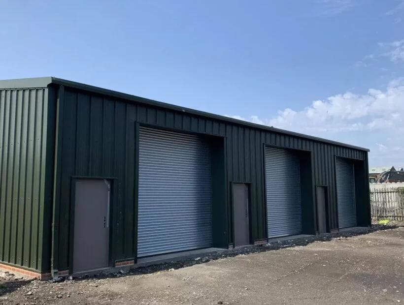 Completed steel unit with three galvanised roller shutter doors and personnel doors